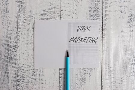 Conceptual hand writing showing Viral Marketing. Concept meaning whereby consumer encouraged share information via Internet Square notebook fine highlighter lying on wooden backgroundの写真素材