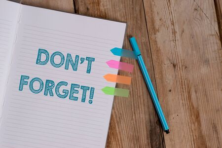 Conceptual hand writing showing Don T Forget. Concept meaning used to remind someone about an important fact or detail Striped notebook colored arrow banners ballpoint wooden backgroundの写真素材