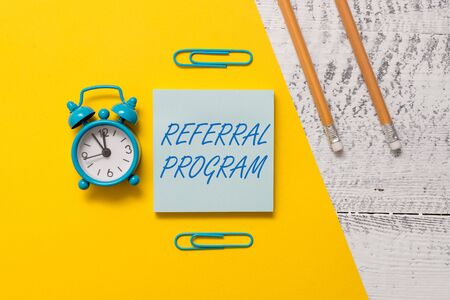 Text sign showing Referral Program. Business photo text sending own patient to another physician for treatment Notepad clips colored paper sheet markers alarm clock wooden backgroundの写真素材