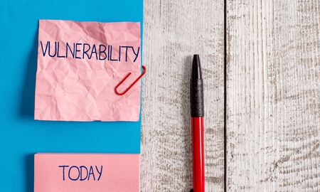 Handwriting text Vulnerability. Conceptual photo State of being exposed to the possibility of being attacked Wrinkle paper and cardboard plus stationary placed above wooden backgroundの写真素材