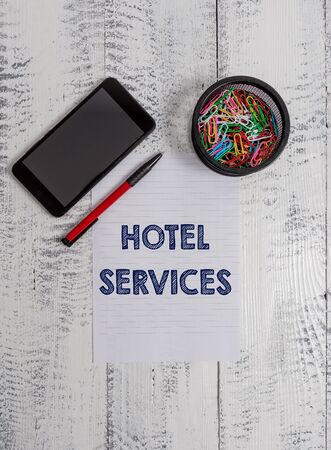 Conceptual hand writing showing Hotel Services. Concept meaning Facilities Amenities of an accommodation and lodging house Smartphone paper sheet clips ballpoint wooden vintage backgroundの写真素材