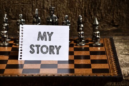 Writing note showing My Story. Business concept for the things or situations that have happened to someone in life Empty Notepad Sheet Folded in Half Chessboard Themed Chess Set Piecesの写真素材