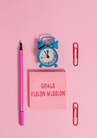 Conceptual hand writing showing Goals Vision Mission. Concept meaning practical planning process used to help community group Metal alarm clock blank notepad marker clips colored backgroundの写真素材