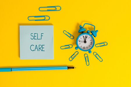Word writing text Self Care. Business photo showcasing the practice of taking action to improve one s is own health Metal alarm clock wakeup clips ballpoint notepad colored backgroundの写真素材
