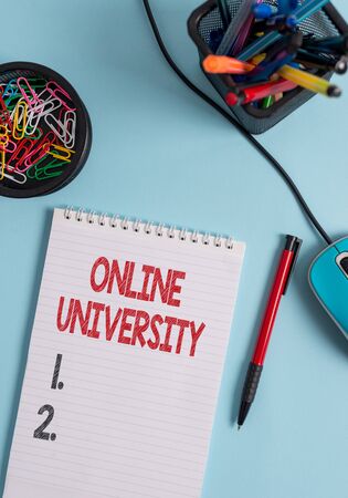 Writing note showing Online University. Business concept for Distance Learning Courses are taken over the internet Notebook and stationary with mouse above pastel backdropの写真素材