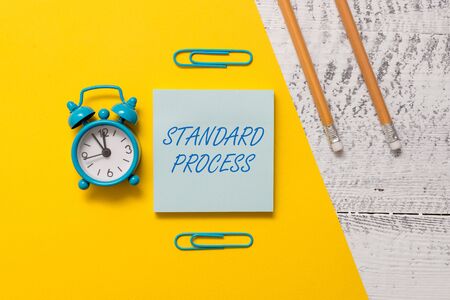 Text sign showing Standard Process. Business photo text rules made to be matched with final product quality Notepad clips colored paper sheet markers alarm clock wooden backgroundの写真素材