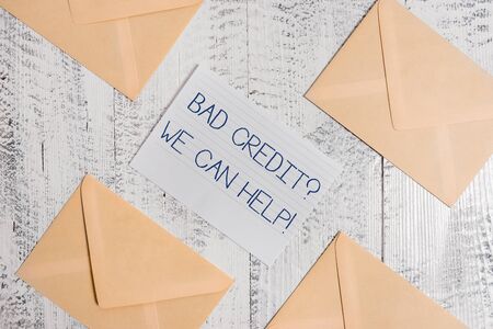 Text sign showing Bad Creditquestion We Can Help. Business photo text offerr help to gain positive payment history Four envelopes around ruled paper sheet old wooden vintage backgroundの写真素材