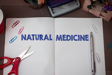 Writing note showing Natural Medicine. Business concept for any of various systems of healing or treating disease Scissors and writing equipments plus math book above textured backdropの写真素材