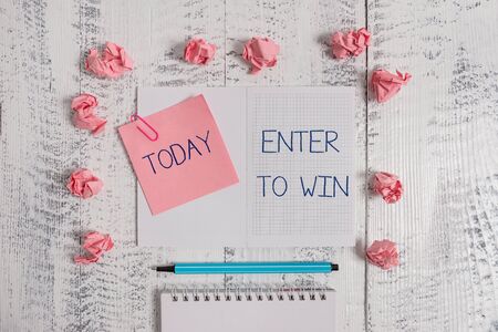 Text sign showing Enter To Win. Business photo text exchanging something value for prize or chance of winning Squared spiral notepad clip note highlighter paper balls wooden backgroundの写真素材