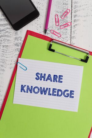 Writing note showing Share Knowledge. Business concept for teaching others what I learnt before Giving lectures Clipboard sheet pencil smartphone squared note clips wooden backgroundの写真素材