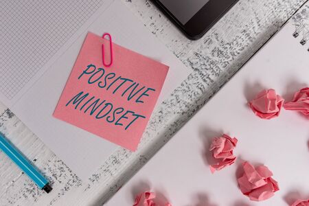 Text sign showing Positive Mindset. Business photo showcasing mental attitude in wich you expect favorable results Squared spiral notebook marker smartphone paper balls note clip woodenの写真素材