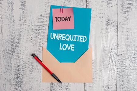 Text sign showing Unrequited Love. Business photo text not openly reciprocated or understood as such by beloved Envelope blank sheet letter paper sticky note ballpoint wooden backgroundの写真素材
