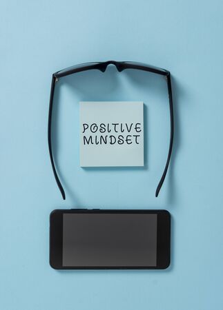 Handwriting text writing Positive Mindset. Conceptual photo mental and emotional attitude that focuses on bright side Dark eyeglasses colored sticky note smartphone fashion pastel backgroundの写真素材