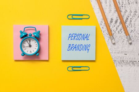 Conceptual hand writing showing Personal Branding. Concept meaning Practice of People Marketing themselves Image as Brands Notepads colored paper sheet markers alarm clock wooden backgroundの写真素材