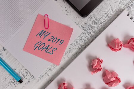 Text sign showing My 2019 Goals. Business photo showcasing setting up demonstratingal goals or plans for the current year Squared spiral notebook marker smartphone paper balls note clip woodenの写真素材
