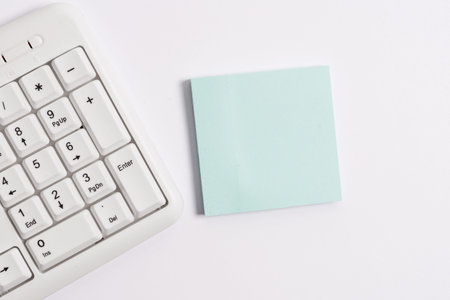 White pc keyboard with empty note paper above white background.