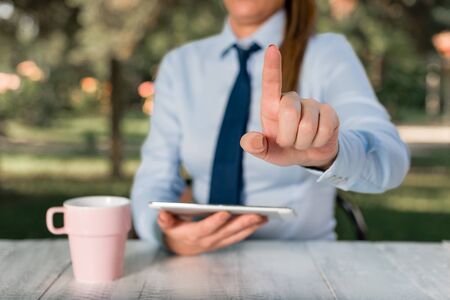 Business concept with female business person sitting by the table and holding mobile phone.の写真素材