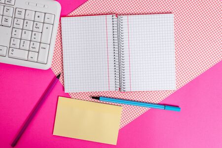 Writing equipments and computer stuffs placed above colored plain tableの写真素材