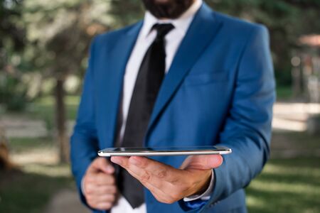 Businessman in blue suite stands with mobile phone in hands.の写真素材