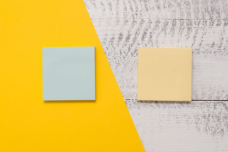 Two multicolor blank notepads colored paper sheet retro wooden background