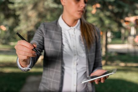 Outdoor background with business woman holding lap top and pen.の写真素材
