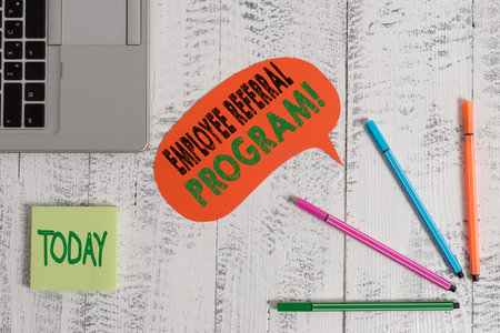 Text sign showing Employee Referral Program. Business photo text internal recruitment method employed by organizations Open laptop speech bubble ballpoints sticky notes vintage wooden tableの写真素材