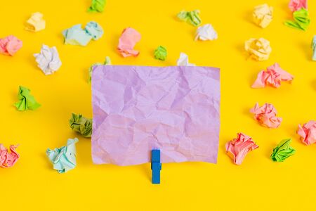 Colored crumpled papers empty reminder white floor background clothespinの写真素材