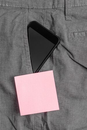 Smartphone device inside formal work trousers front pocket near note paperの写真素材