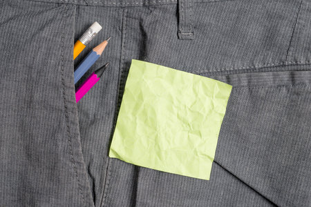 Writing equipment and green note paper inside pocket of man work trousers
