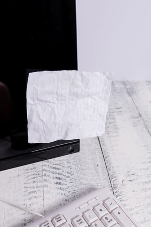 Notation paper taped to black computer monitor screen near white keyboard