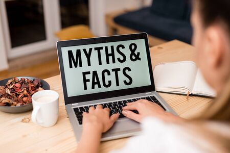 Handwriting text Myths And Facts. Conceptual photo usually traditional story of ostensibly historical events woman laptop computer smartphone mug office supplies technological devicesの写真素材