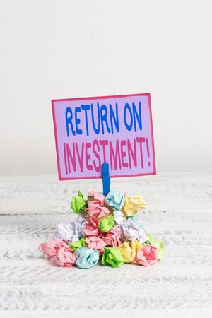 Conceptual hand writing showing Return On Investment. Concept meaning perforanalysisce measure used evaluate efficiency of investment Reminder pile colored crumpled paper clothespin wooden spaceの写真素材