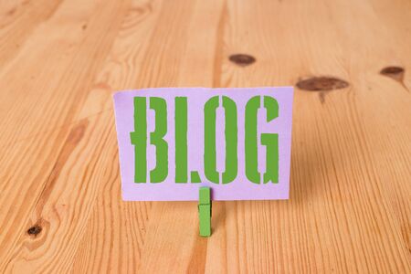 Writing note showing Blogquestion. Business concept for regularly updated website web page run by individual Wooden floor background green clothespin groove slot officeの写真素材