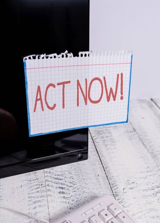 Text sign showing Act Now. Business photo text do not hesitate and start working or doing stuff right away Notation paper taped to black computer monitor screen near white keyboardの写真素材