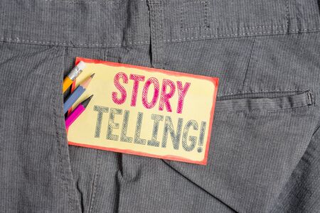 Conceptual hand writing showing Story Telling. Concept meaning activity writing stories for publishing them to public Writing equipment and yellow notepaper in pocket of trousersの写真素材