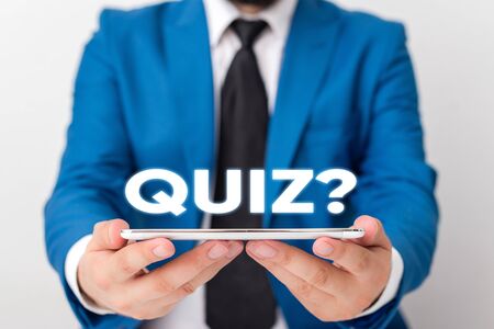 Handwriting text writing Quiz Question. Conceptual photo test of knowledge as competition between individuals or teams Businessman in blue suite with a tie holds lap top in handsの写真素材