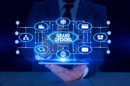 Text sign showing Grand Opening. Business photo text Ribbon Cutting New Business First Official Day Launching Male human wear formal work suit presenting presentation using smart deviceの写真素材