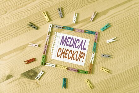 Handwriting text writing Medical Checkup. Conceptual photo thorough physical examination includes variety of tests Colored clothespin papers empty reminder wooden floor background officeの写真素材