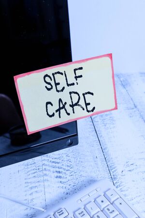 Word writing text Self Care. Business photo showcasing the practice of taking action to improve one s is own health Notation paper taped to black computer monitor screen near white keyboardの写真素材