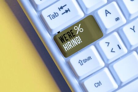 Text sign showing We Re Hiring. Business photo showcasing process of reviewing applications and finding candidates White pc keyboard with empty note paper above white background key copy spaceの写真素材