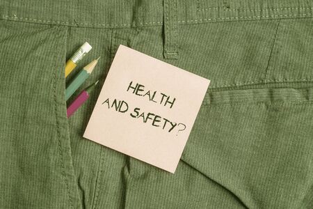 Conceptual hand writing showing Health And Safety Question. Concept meaning regulations and procedures to prevent accident or injury Writing equipment and pink note paper inside pocket of trousersの写真素材