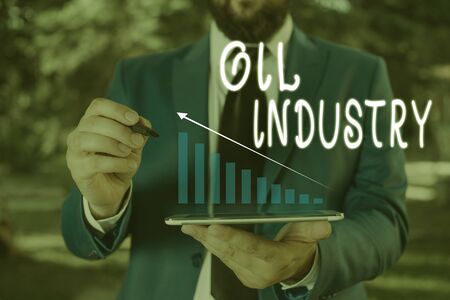 Word writing text Oil Industry. Business photo showcasing Exploration Extraction Refining Marketing petroleum products Male human wear formal work suit presenting presentation using smart deviceの写真素材