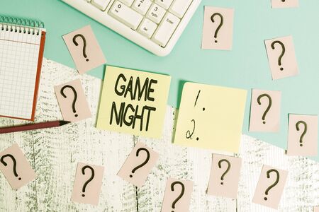 Conceptual hand writing showing Game Night. Concept meaning event in which folks get together for the purpose of getting laid Writing tools and scribbled paper on top of the wooden tableの写真素材