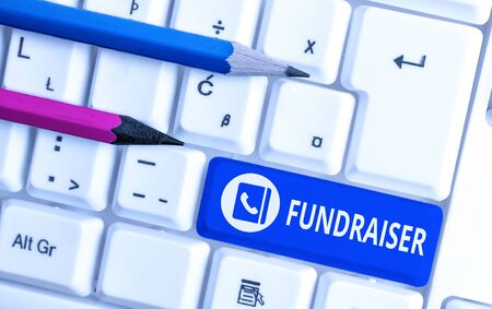 Writing note showing Fundraiser. Business concept for demonstrating whose job or task is seek financial support for charity White pc keyboard with note paper above the white backgroundの写真素材