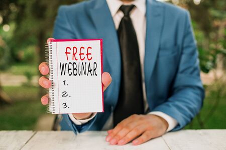 Text sign showing Free Webinar. Business photo text Lecture Workshop Seminar that is transmitted over the Web Man holds empty paper with copy space in front of himの写真素材