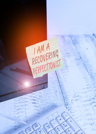 Word writing text I Am A Recovering Perfectionist. Business photo showcasing Obsessive compulsive disorder recovery Notation paper taped to black computer monitor screen near white keyboardの写真素材