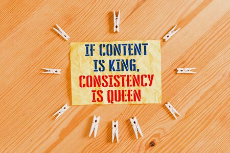 Writing note showing If Content Is King Consistency Is Queen. Business concept for Marketing strategies Persuasion Colored clothespin papers empty reminder wooden floor background officeの写真素材