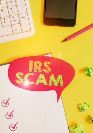 Handwriting text Irs Scam. Conceptual photo targeted taxpayers by pretending to be Internal Revenue Service Empty red bubble paper on the table with pc keyboardの写真素材