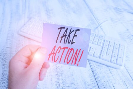 Text sign showing Take Action. Business photo showcasing do something official or concerted to achieve aim with problem man holding colorful reminder square shaped paper white keyboard wood floorの写真素材