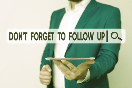 Text sign showing Don T Forget To Follow Up. Business photo showcasing asking someone to keep connection with others Man in the blue suite and white shirt holds mobile phone in the handの写真素材